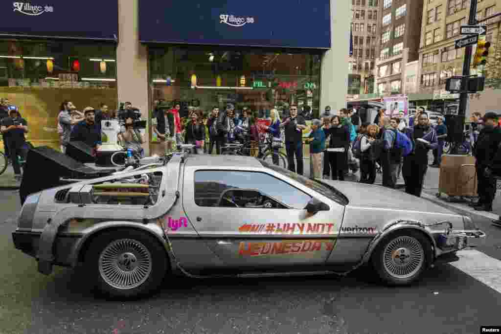 Pedestrians stop to look at and photograph a DeLorean Motor Company DMC-12, customized to look identical to the car used in the film &quot;Back to the Future Part II&quot;, and that will be part of a Lyft promotion, in New York, Oct. 21, 2015.