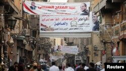 People walk under posters of Egyptian President Abdel Fattah al-Sissi for the upcoming presidential election, in Cairo, Egypt, March 19, 2018. 