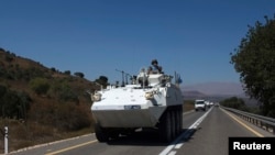 A member of the U.N. Disengagement Observer Force (UNDOF) rides atop an armored vehicle near the Quneitra border crossing on the Israeli-occupied Golan Heights, Aug. 28, 2014. 