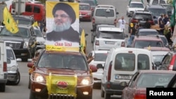 FILE - A man gestures as he drives a car with the picture of Hezbollah leader Sayyed Hassan Nasrallah on it, during the parliamentary election day, in Bint Jbeil, southern Lebanon, May 6, 2018. 
