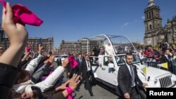 In this photo provided by the office of the Mexican president, Pope Francis waves to the crowd from the popemobile on Zocalo Square in Mexico City, Feb. 13, 2016.