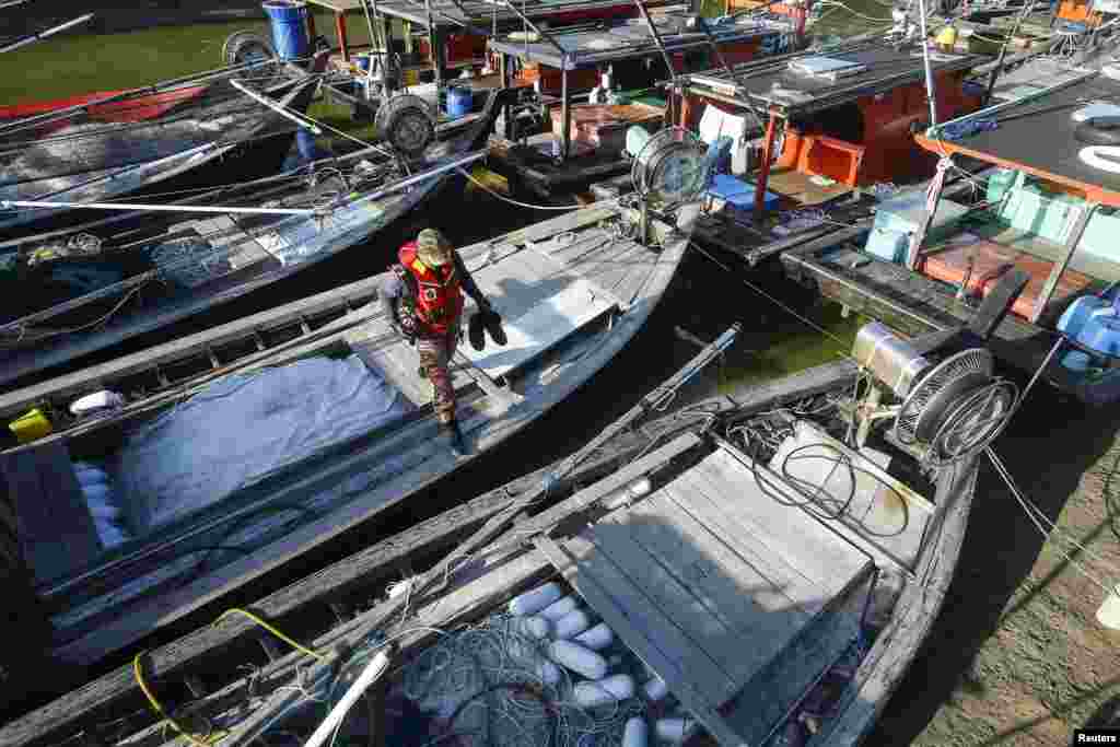 A firefighter walks on fisherman's boat during a search and rescue in Kuala Langat outside Kuala Lumpur, off Malaysia's western coast, June 18, 2014. 