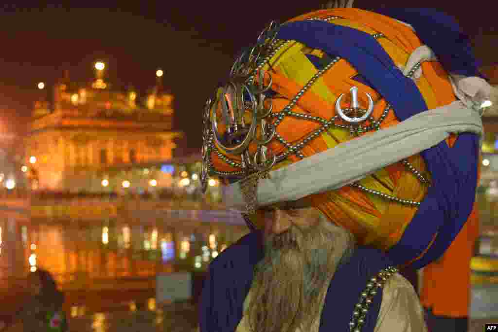 An Indian Sikh Nihang (a traditional Sikh religious warrior) Baba 'Avtar' Singh wears an oversized traditional turban as he pays respects at the Golden temple in Amritsar on the eve of the Indian festival of Diwali, the festival of lights, Nov. 10, 2015.