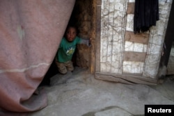 FILE - A boy displaced from the Red Sea port city of Hodeida looks from behind a door curtain in a shelter in Sanaa, Yemen, Nov. 2, 2018.