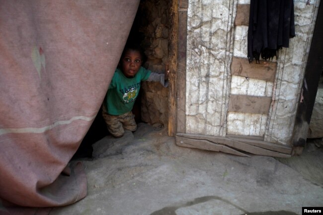 FILE - A boy displaced from the Red Sea port city of Hodeida looks from behind a door curtain in a shelter in Sanaa, Yemen, Nov. 2, 2018.
