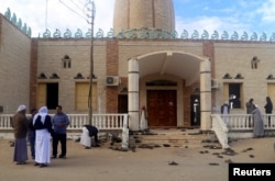 FILE - People stand outside Al Rawdah mosque, which was hit by a bomb attack, in Bir al Abed, Egypt, Nov. 25, 2017. The attack killed more than 300 people.