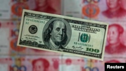 FILE - A photo illustration shows a $100 banknote placed above Chinese 100 yuan banknotes in Beijing. 