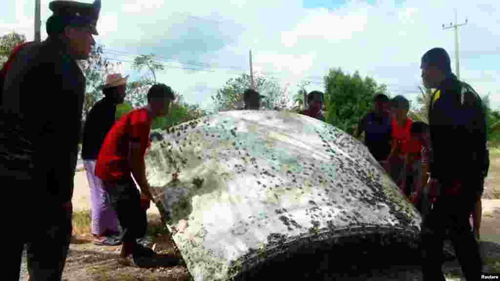 People stand next to a piece of suspected plane wreckage which has been found off the coast of southern Thailand in Nakhon Si Thammarat province, Jan. 24, 2016. 