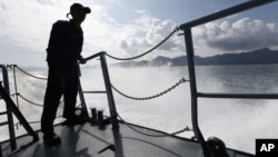 A member of Malaysian Navy is silhouetted as he stands guard on the bow of a corvette ship during a media trip for the search and rescue mission of Rohingya migrants in Langkawi, Malaysia on Thursday, May 28, 2015.