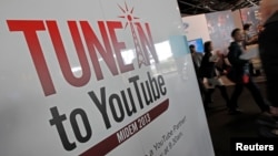 Visitors walk past a YouTube stand during the International Record Music Publishing and Video Music Market (MIDEM) in Cannes, France, Jan. 27, 2013. 