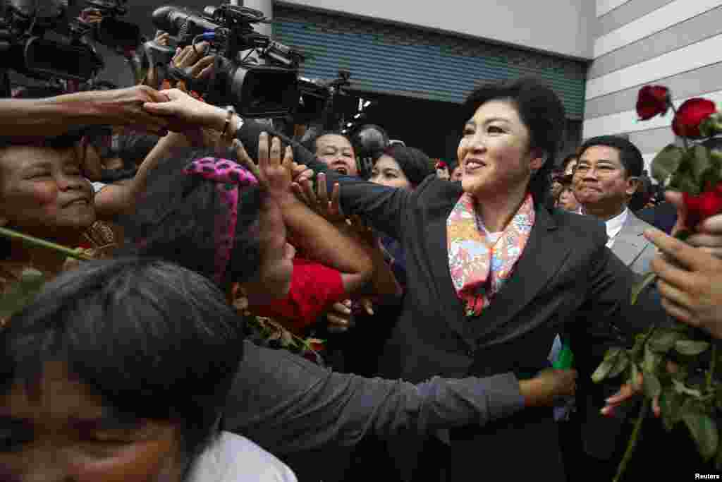 Perdana Menteri Thailand Yingluck Shinawatra menyapa para pendukungnya saat meninggalkan kantor Menteri Pertahanan di Bangkok (7/5). (Reuters/Athit Perawongmetha)