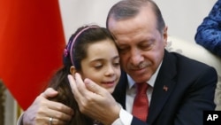 Turkey's President Recep Tayyip Erdogan, embraces Bana Al-Abed, 7, from Aleppo, Syria, at his Presidential Palace in Ankara, Dec. 21, 2016.