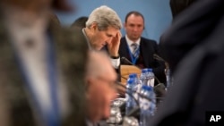 U.S. Secretary of State John Kerry, center, waits for the start of a round table meeting of the NATO-Ukraine Commission at NATO headquarters in Brussels Dec. 2, 2014.