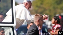 Pope Francis reaches from the popemobile for a child that is brought to him, during a parade in Washington, Wednesday, Sept. 23, 2015. (AP Photo/Alex Brandon, Pool)