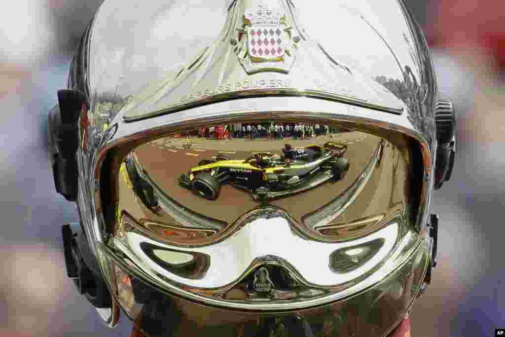 The car of Renault driver Nico Hulkenberg of Germany is reflected in a firemen's helmet visor during the first practice session for the Monaco Formula One Grand Prix at the Monaco racetrack.
