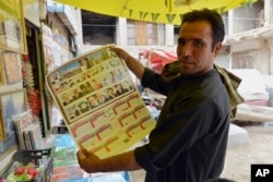An Afghan store clerk shows a calendar with pictures of Afghan leaders including Mullah Mohammad Omar, bottom row, second left, in Kandahar, south of Kabul, Afghanistan, July 30, 2015.