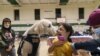 Leanna Arcila, de 7 años, recibe un lengüetazo de Watson, un perro de terapia en el Departamento de Policía de Pawtucket, mientras le aplican su vacuna contra el COVID-19 el martes 7 de diciembre de 2021, en la escuela primaria Nathanael Greene, en Pawtucket, Rhode Island, EE.UU.