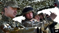 Ukrainian President Petro Poroshenko, left, watches a military exercise of the Ukrainian armed forces in Mykolaiv region, Ukraine, April 25, 2015. 