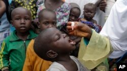 FILE - A health official administers a polio vaccine to children at a camp for people displaced by Islamist Extremist in Maiduguri, Nigeria, Aug. 28, 2016. 