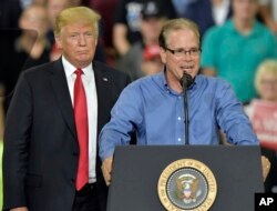 As President Donald Trump, left, looks on, Republican Mike Braun, speaks to a group of supporters during a Rally at the Ford Center in Evansville, Ind., Aug. 30, 2018.