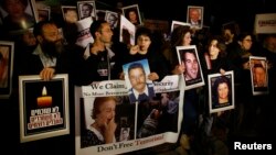 Israelis hold placards depicting people who were killed in pro-Palestinian attacks during a protest against the release of Palestinian prisoners, outside Israel's Prime Minister Benjamin Netanyahu's residence in Jerusalem, Mar. 26, 2014.
