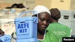 A Nigerian local health worker carries vaccination kits at a distribution center ahead of the start of a nation-wide polio immunization campaign, Lagos.