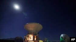 FILE - Moon shines over Chilean radio antennas that link as a single giant telescope, much like components of planned project in Mauana Kea, on Hawaii's Big Island.