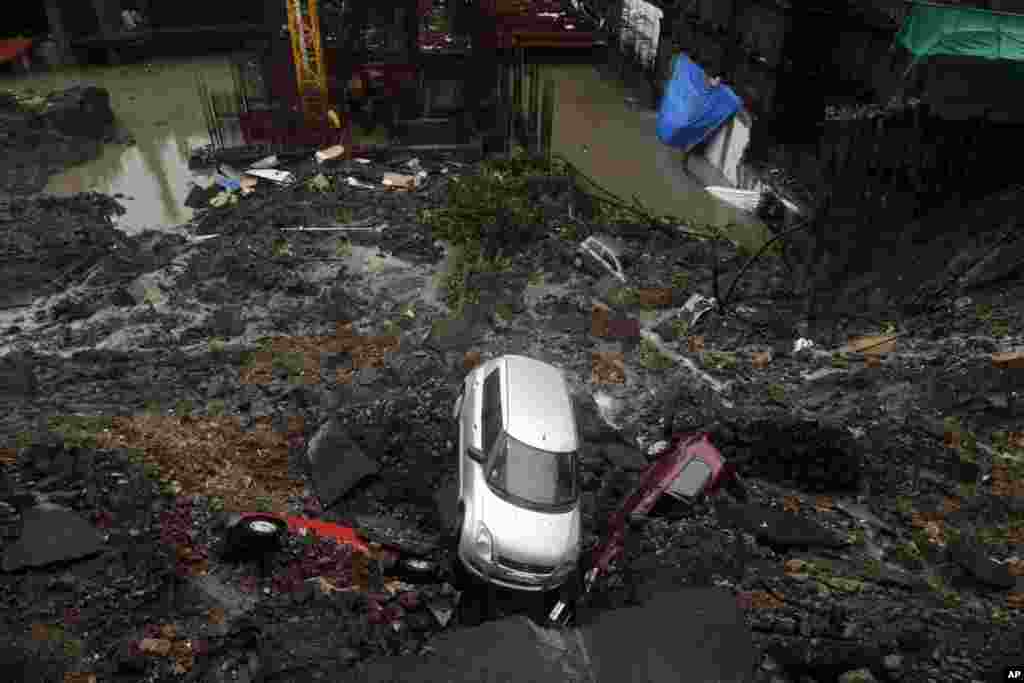 Cars lie buried in debris after the wall of a building under construction collapsed during heavy rains in Mumbai, India.