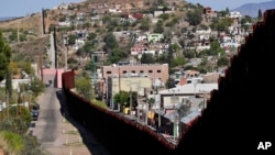 FILE - The United States-Mexico international border cuts through Nogales, Ariz., with the U.S., left, and Mexico, right. The U.S. Army put six rows of concertina wire on top of the two-story border wall. The city council of Nogales, Ariz., wants it removed or it will sue.