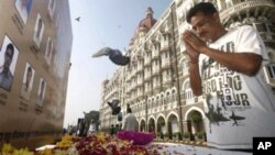 A man pays homage in front of portraits of police officers killed in the Mumbai terror attacks outside the Taj Mahal Palace hotel on Nov. 26, 2010, the second anniversary of the attacks.