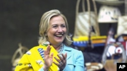 Secretary of State Hillary Rodham Clinton wraps herself with chitenge material after she was presented with it by members of the African Women's Entrepreneurship Program at the Mulungushi International Conference Center in Lusaka, Zambia, Friday, June 10,