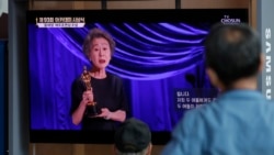 Warga menyaksikan penayangan siaran langsung "The Academy Awards" di Stasiun Kereta Seoul di Seoul, Korea Selatan, yang menampilkan aktris Korea Selatan Yuh-Jung Youn tsaat memberikan sambutan sambil memegang piala Oscar sebagai aktris pendukung terbaik dalam film "Minari", Senin, 26 April 2021. (foto: AP)