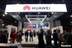 FILE - Attendees pass by a Huawei booth during the 2019 CES in Las Vegas, Nevada, U.S. Jan. 9, 2019.
