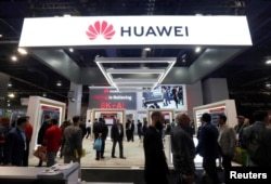 FILE - Attendees pass by a Huawei booth during the 2019 CES in Las Vegas, Jan. 9, 2019.