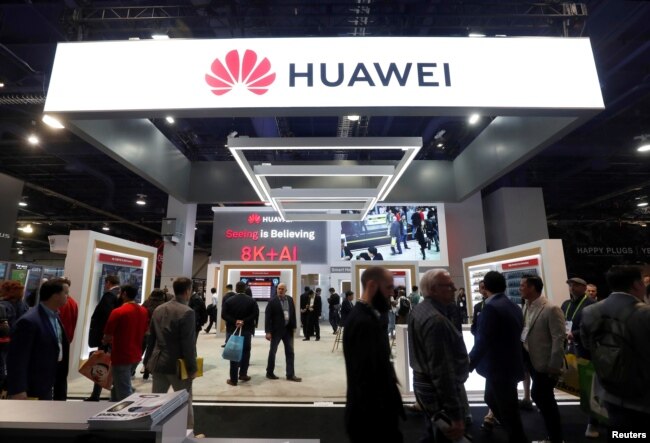 FILE - Attendees pass by a Huawei booth during the 2019 CES in Las Vegas, Jan. 9, 2019.