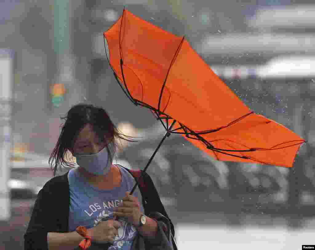 A woman holds her umbrella while walking against strong winds as Typhoon Matmo hits Taipei, July 23, 2014.