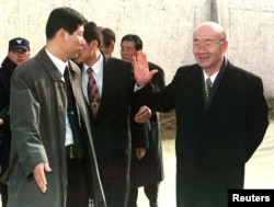 FILE - Former South Korean president Chun Doo-hwan, right, waves goodbye as he is escorted by a secret service agent outside the walls of Anyang Prison to a waiting car shortly after being released from the jail on a special pardon in Anyang, Dec. 22, 199