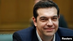 Greek Prime Minister Alexis Tsipras smiles as he attends the first meeting of the new cabinet in the parliament building in Athens, Jan. 28, 2015. 