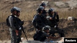 Seorang polisi perbatasan Israel membidik senjatanya ke warga Palestina dalam bentrokan dengan warga Palestina di titik pemeriksaan Hawara, Israel dekat kota Tepi Barat Nablus, 16 Oktober 2015. (REUTERS/Ahmad Talat)