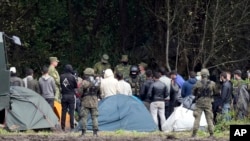 FILE - Polish security forces surround migrants stuck along with border with Belarus in Usnarz Gorny, Poland, Sept. 1, 2021.