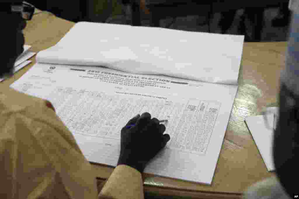 As Nigerians await results in the tightest and most bitterly contested presidential election in the nation's history, a Nigerian election official reads local results in Kaduna, March 30, 2015.