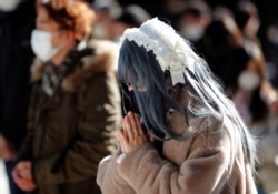 People wearing protective masks amid the coronavirus disease (COVID-19) outbreak, pray on the first day of the new year at the Meiji Shrine in Tokyo, Japan, January 1, 2021. REUTERS/Kim Kyung-Hoon