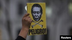 A protester holds a sign with an image of former president Alberto Fujimori with the word 'Danger' during a march against a possible pardon for Fujimori, Lima, Peru, July 7, 2017. 