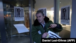 U.K. -- A man fixes posters depicting Cambridge Analytica's CEO Alexander Nix behind bars, with the slogan "Our Data Not His. Go Straight To Jail" to the entrance of the company's offices in central London, March 20, 2018