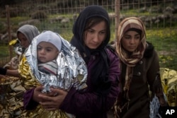 FILE - Women and children stand on a road after their arrival on a dinghy with other refugees and migrants from the Turkish coast to the Greek island of Lesbos, on Wednesday, Nov. 25, 2015.