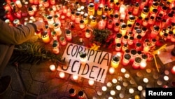 FILE - A banner reading "Corruption kills" is seen among candles, lit in memory of dozens of people killed in a night club fire in Bucharest blamed on official graft, at a memorial in Timisoara, Romania, Nov. 1, 2015.