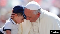 El Papa abraza a un niño al llegar a la Plaza de San Pedro el miércoles 19 de junio para su audiencia semanal.