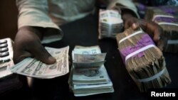 FILE - A trader changes dollars with naira at a currency exchange store in Lagos, Feb. 12, 2015. 