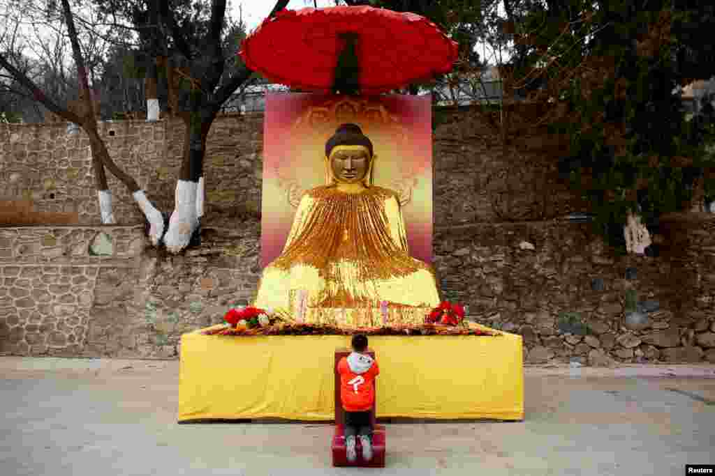 دعا و نیایش یک پسر بچه مقابل معبد بودایی ها به مناسبت فرا رسیدن سال نو چینی یا فستیوال بهار در چین &nbsp;