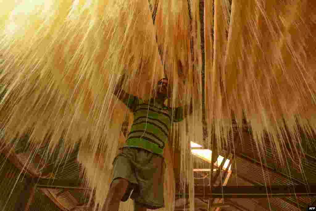 An Indian worker arranges strands of vermicelli noodles to dry inside of a factory during the Muslim holy fasting month of Ramadan on the outskirts of Agartala.